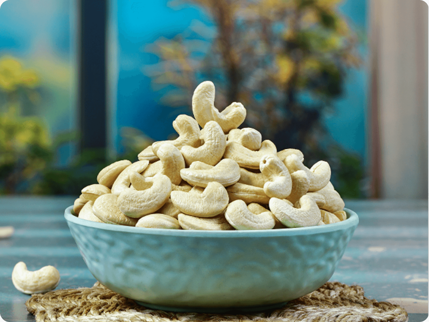 Light blue bowl overflowing with whole cashews